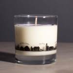 White candle in a clear glass tumbler with a city skyline design