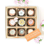 Box of decorated chocolates with pink flowers and a note card