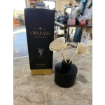 Reed diffuser with cream flower-shaped reeds beside a black box