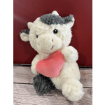 Plush cow holding a pink heart against a red background