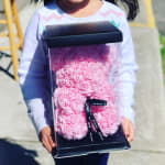 Child holding a clear box filled with pink rose-shaped flowers