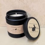 Black jar candle with a lid beside it