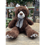 Brown teddy bear with a striped scarf sitting on a table