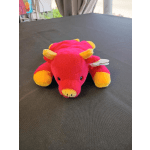 Pink and yellow plush pig toy on a dark table