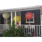 Large balloons in cream, yellow, and pink hang on a porch.