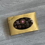 Box of assorted chocolates with a gold wrapper and window cutout