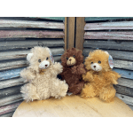 Three plush teddy bears in cream, brown, and orange sitting together