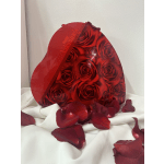Heart-shaped box of red roses with scattered rose petals