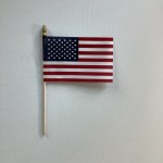 Small American flag on a wooden stick against a plain background
