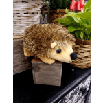 Plush hedgehog toy on a wooden block beside wicker baskets