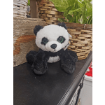 Plush panda bear sitting among woven baskets and potted plants