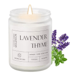 Lavender thyme scented candle in a glass jar with purple flowers beside it