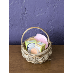 Woven gift basket filled with boxed soaps and a pink scrub brush on a wooden table