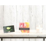 Colorful square candle with a glass votive and a small card on a shelf
