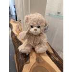 Small plush teddy bear with a polka-dot bow sitting on a wooden surface
