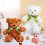 Two teddy bears with green bows beside small sweets and flowers