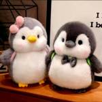 Two plush penguin toys sitting on a wooden shelf
