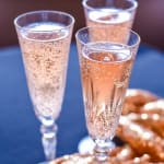 Three champagne flutes filled with sparkling rosé on a table