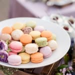 Plate of pastel macarons with a few purple flowers nearby