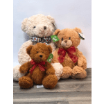 Three teddy bears with ribbon bows sit together on a wooden surface.