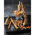 Chocolate-dipped pretzel rods and candy in a glass dish