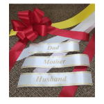 Red gift ribbons and white satin name ribbons on a carpeted surface
