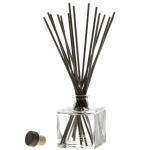 Glass reed diffuser bottle with black reeds and a cap beside it