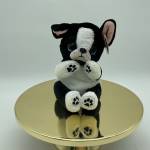 Black-and-white plush puppy sitting on a gold round stand