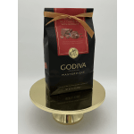 A bag of Godiva milk chocolates tied with a gold ribbon on a gold pedestal stand
