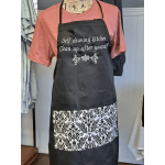 Black apron with white text over a pink shirt