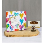 Heart-patterned chocolate gift box on a wooden board with a small flower-shaped card holder.