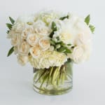White roses and hydrangeas arranged in a clear glass vase