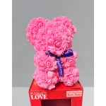 Pink rose teddy bear with a purple ribbon on a red box