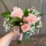 Handheld bouquet of pale pink roses and white baby's breath