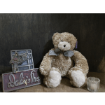Teddy bear with a bow beside a decorative shop sign and glass votive holder