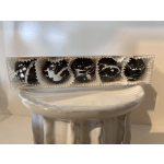 Box of five dark chocolate truffles with white splatter decoration on a white pedestal
