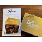 Gold box of assorted chocolates with branded card on a wooden surface
