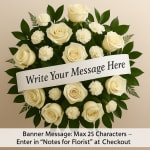 White roses and carnations arranged in a circular wreath with a message banner