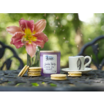 Pink lily in a vase beside a purple candle, cookies, and a teacup