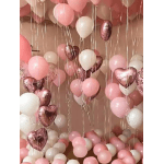 Pink, white, and metallic heart balloons fill a room.