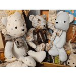 Three fabric teddy bears with bows sit in a drawer display.