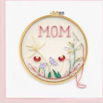 Quilled paper art in an embroidery hoop spelling MOM with floral designs