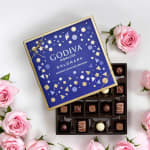 Box of assorted chocolates surrounded by pink roses