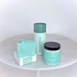 Three mint-green bath products arranged on a round table.