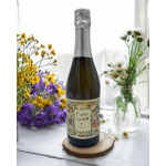 A prosecco bottle on a wood slice with small flower arrangements nearby