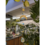 Hanging crystal and gold moon ornament in a plant shop