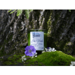 Green candle with a purple flower beside it on moss