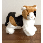 Plush calico cat toy standing on a wooden surface