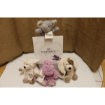 Three plush animals sit around a Warmies display box.
