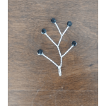 Small decorative branch with black beads on a wooden surface